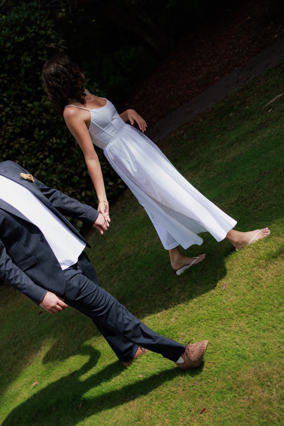 A couple rolling down a grassy bank, laughing