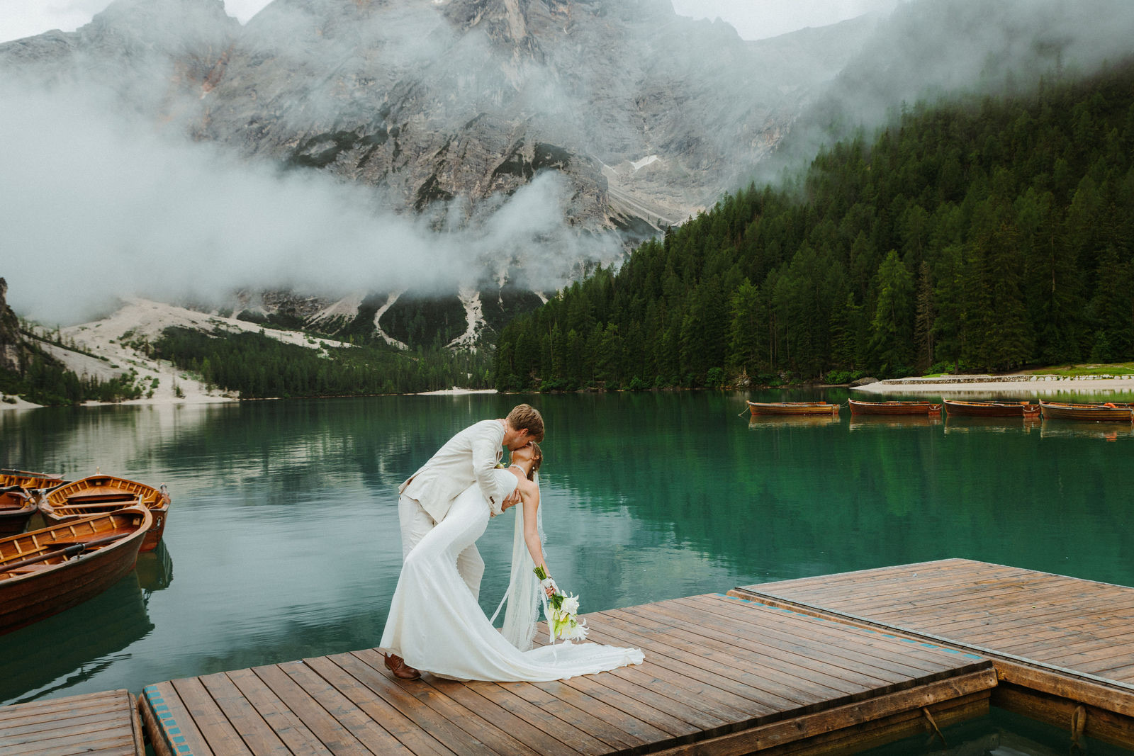 A couple on a jetty by an alpine lake on their elopement day